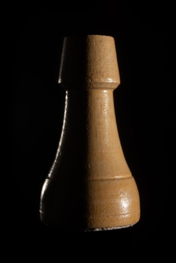 A wooden chess piece against a black background